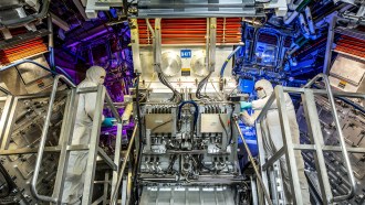 Two workers stand in front of equipment at the National Ignition Facility.